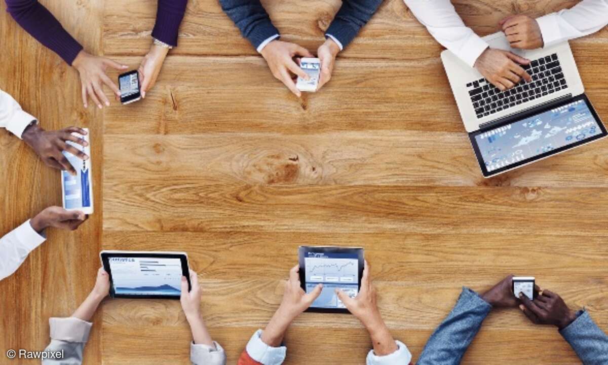 Menschen mit mobilen Geräten am Tisch