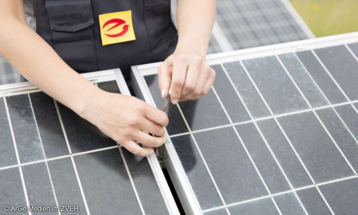 Technikerin schraubt an Photovoltaik-Anlage