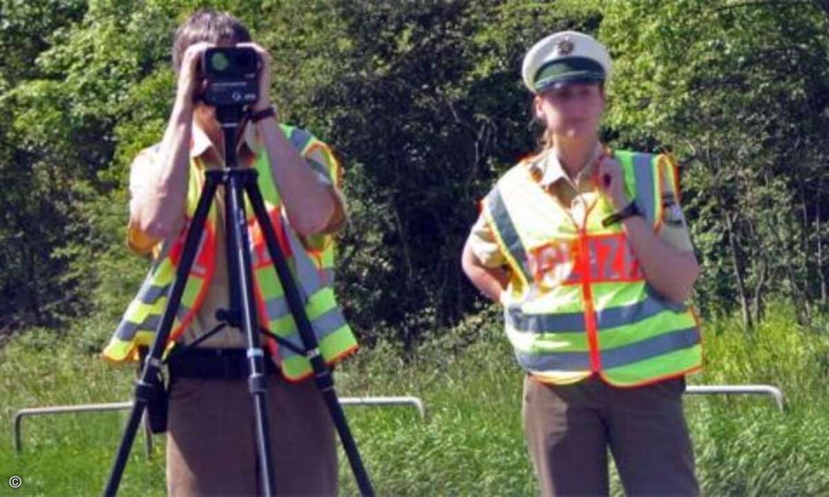 Polizeibeamter bei Geschwindigkeitskontrolle mit Laser-Messgerät auf einem Stativ montiert. (Foto: VisualBeo at de.wikipedia)