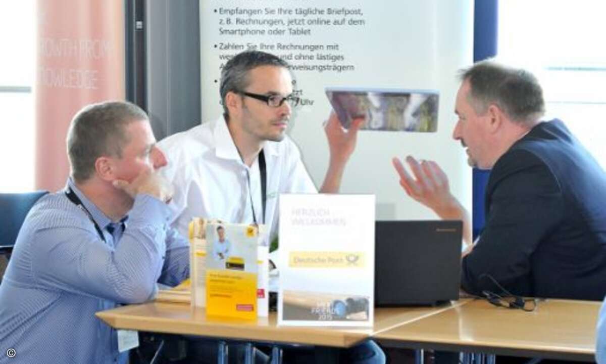 René Krause und Marko Strzebin (Galeon Computer) informieren sich bei Oliver Großmann von der Deutschen Post über die E-Postbusiness Box (Foto: emendo)