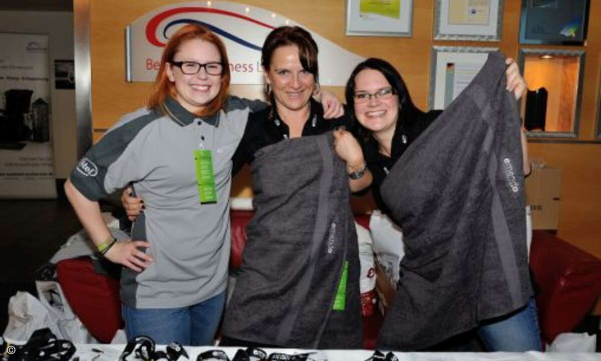 Spaß am Empfang: Karoline Helms, Beata Megger und Miriam Pöttker von emendo begrüßten die Gäste mit Handtüchern und Shirts – natürlich im emendo-Look (Foto: emendo)