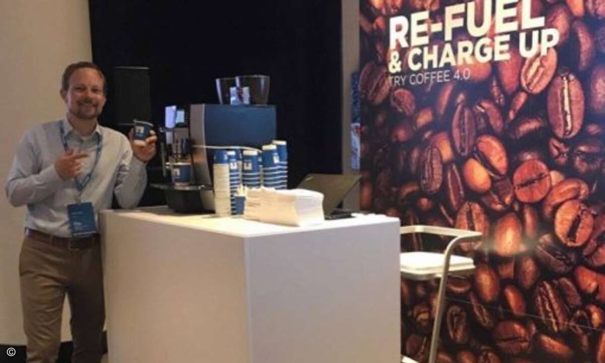Stefan Ebener neben einer Standard-Kaffeemaschine, die mit einem kleinen Modul smart gemacht wurde und Verbrauchs- sowie Wartungsdaten zur Auswertung übermittelt – auch das sind Geschäftsfelder, in denen NetApp mittlerweile aktiv ist (Foto: NetApp)