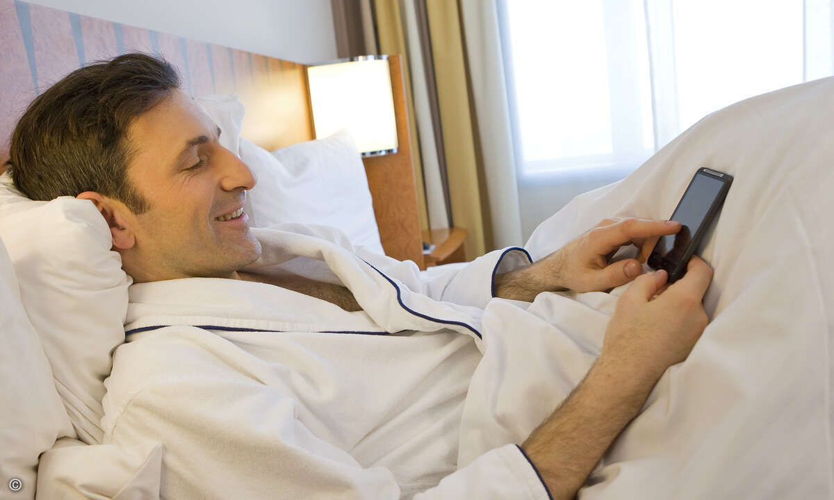 Kaspersky_Mann_mit_Smartphone_Bett