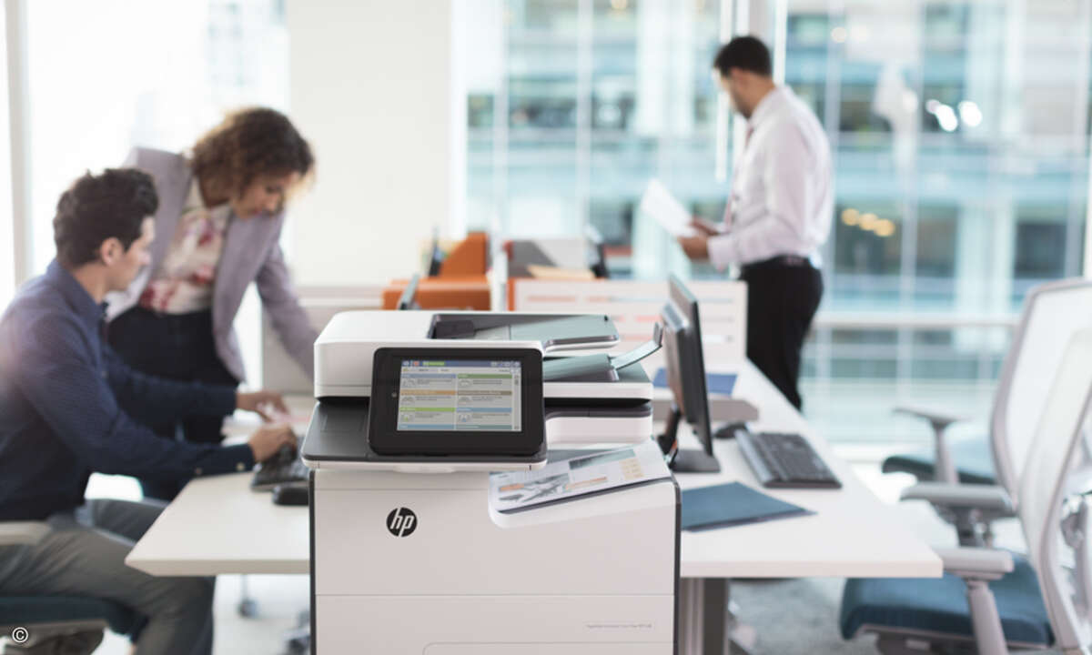 Office workers looking over prints from the HP PageWide Enterpri
